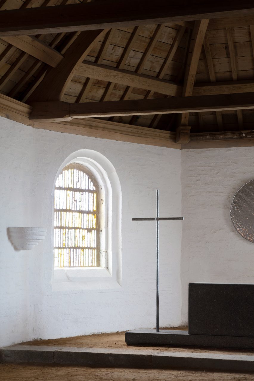 A steel cross positioned inside the chapel alongside the granite altar.