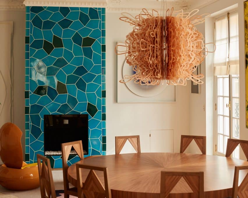 A turquoise fireplace designed by Sarah Crowner adds a bold element to the dining space.