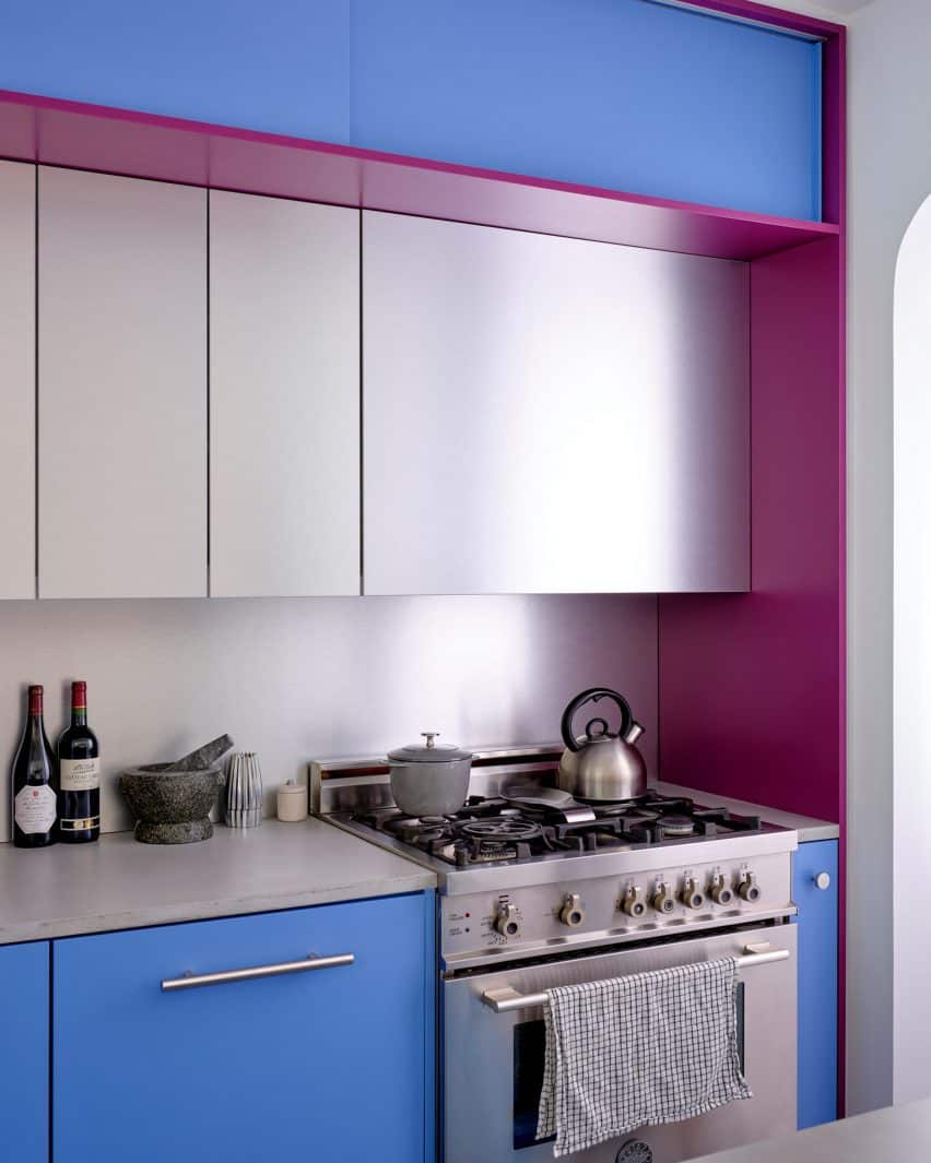 A cooking space surrounded by raspberry and periwinkle cabinetry, enhanced with aluminum panels.
