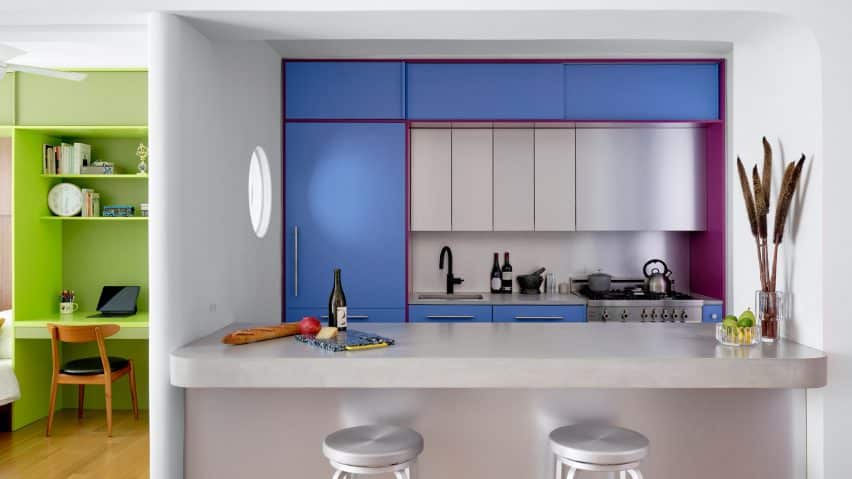 The kitchen showcases blue and purple cabinets contrasted with a sleek concrete counter.