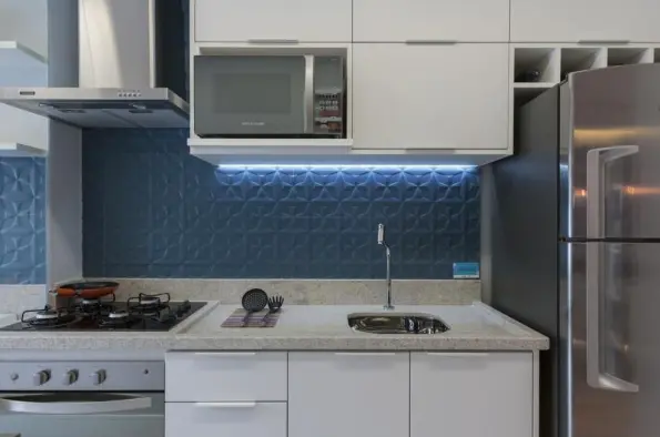 Stunning Ceramic Designs for Your Kitchen: Essential Tips to Choose. 6 Ceramic for kitchen: blue wall covering, custom white carpentry furniture, granite countertop with black cooktop and stainless steel hood – Project: Adriana Fontana