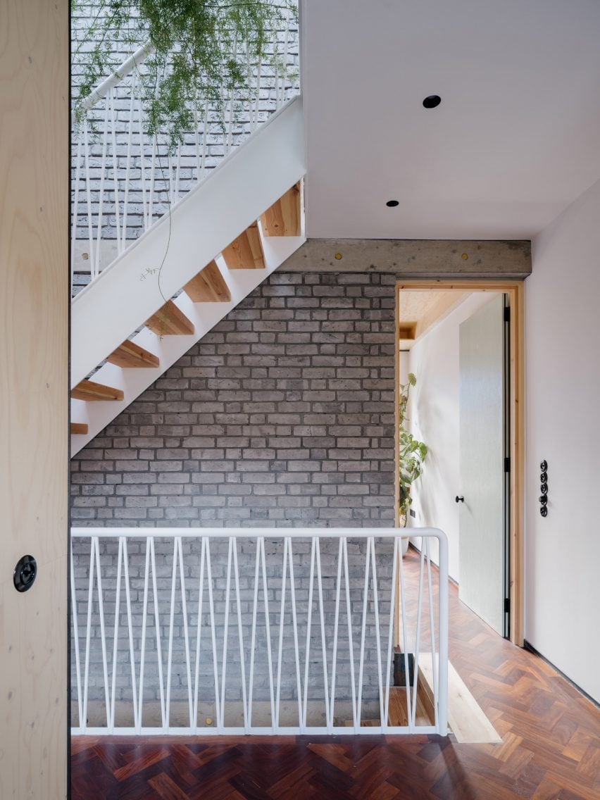 The grey brick spine wall runs the full height of the home, creating a unique design feature that supports the staircase.