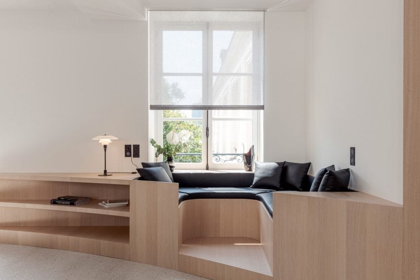 A stylish built-in window seat in Nicolai Paris by NOA functions as both seating and storage space in a converted hotel.