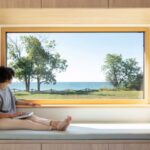 A wooden window seat offers a picturesque view of Lake Ontario in Ell House, designed by Ravi Handa Architect and AAmp Studio.