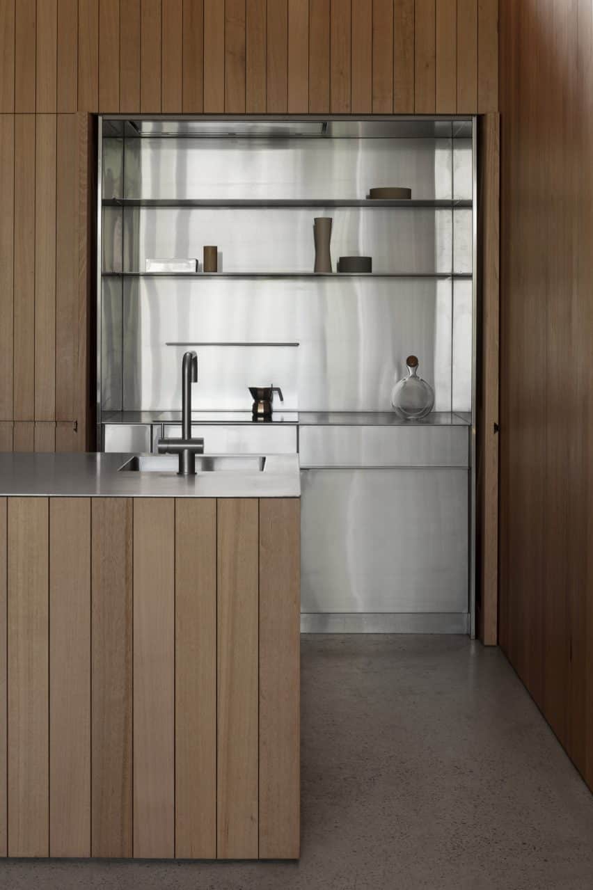 The kitchen is designed beneath the extension's slanted roof with hardwood accents and modern storage solutions.