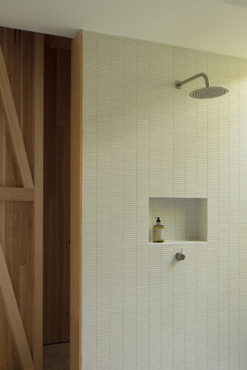 A minimalist bathroom features narrow rectangular tiles that align with the precise project grid.