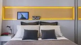Imagem de uma cabeceira iluminada com LED em um quarto.