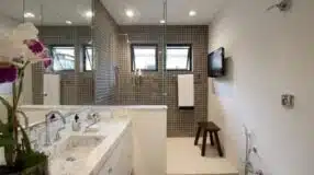 Um banheiro reformado com revestimento cinza.