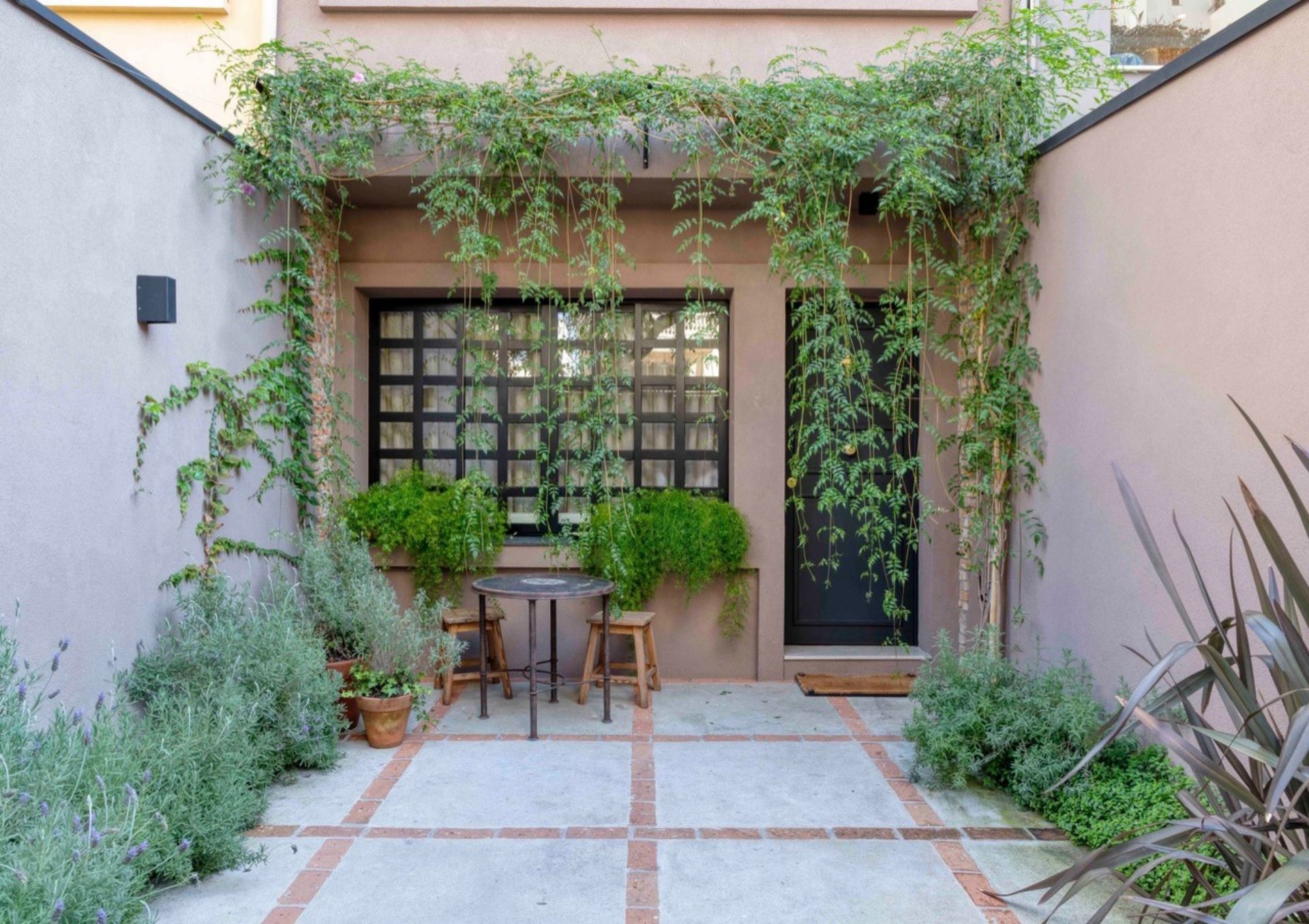 Fachada casa rosa com jardim na entrada.