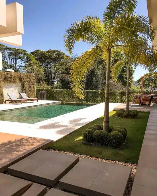 Patio de uma casa com piscina e revestimento natural de plantas.