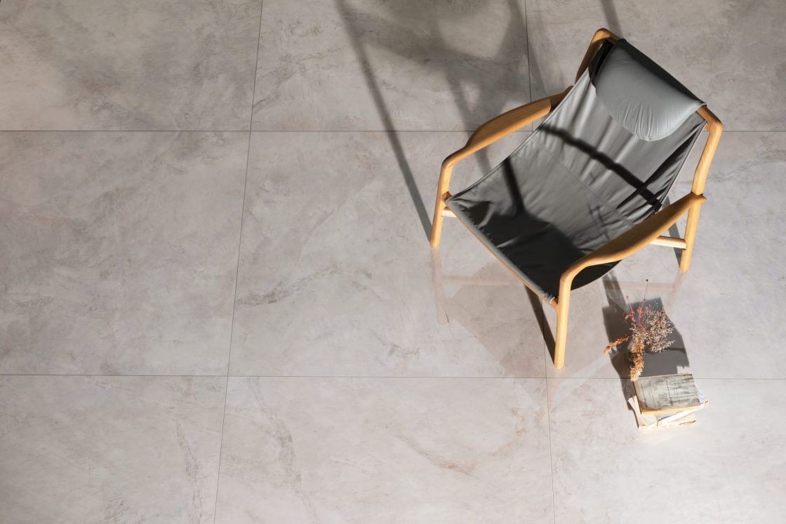 Porcelanato 120x120 visto de cima. Há uma cadeira cinza sobre ele