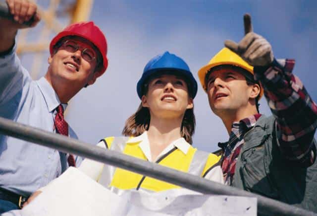 Grupo de arquitetos em uma obra com estruturas em construção.