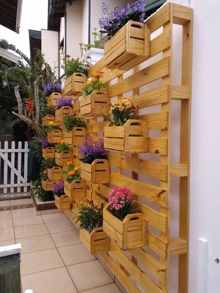 Parede verde de pallet e caixas de madeira, aproveitando materiais reutilizados.