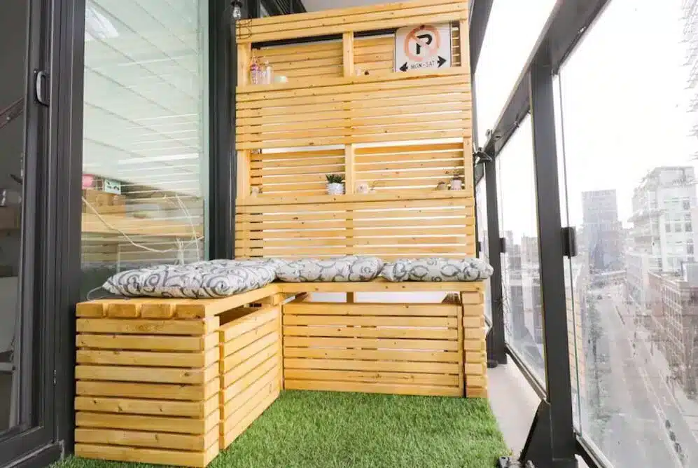 Varanda com móveis de madeira, banco embutido e espaço para plantas, ideal para armazenamento e assentos adicionais.