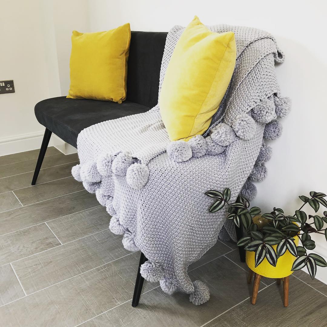 Espaço decorado com almofadas e vaso de planta, ambos em tons de amarelo.