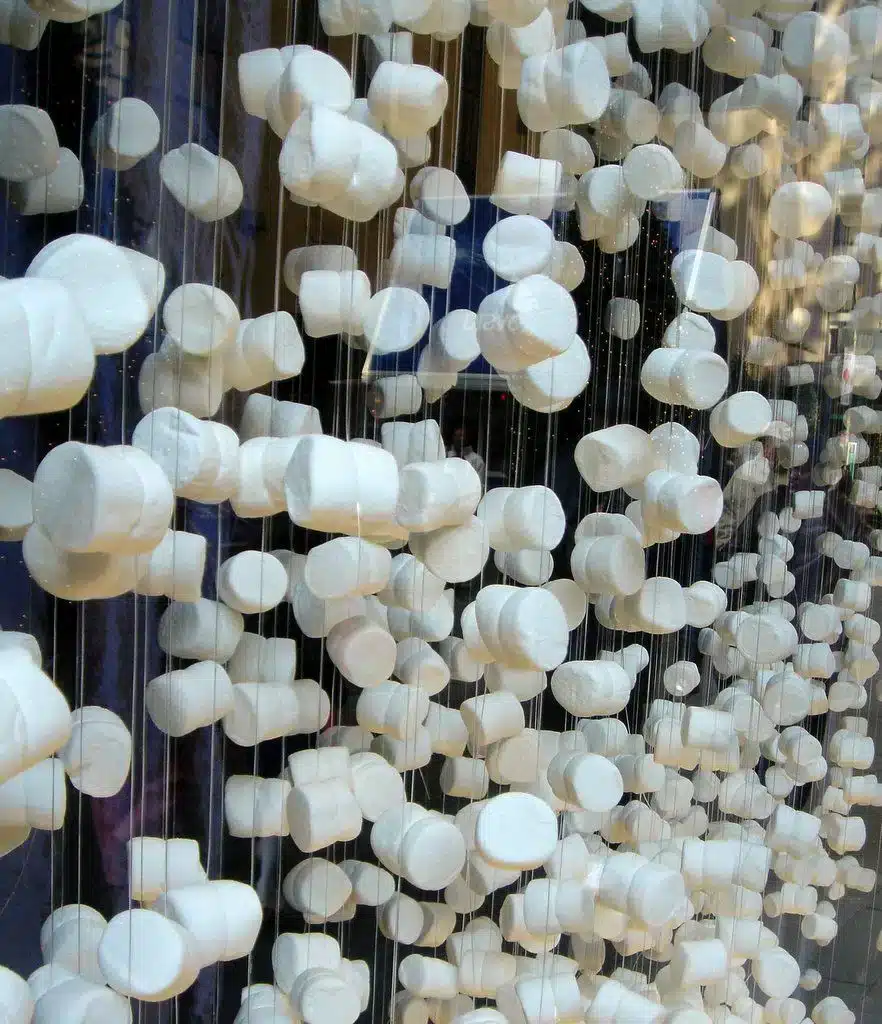 Vitrine de Natal com guirlandas feitas de marshmallow, criando um fundo tridimensional.