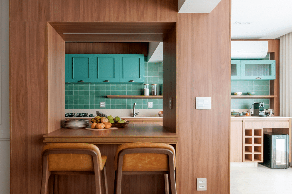 Cozinha e área gourmet integradas por elementos em madeira. O revestimento em madeira também pode ser utilizado para integrar ambientes (Projeto: Paiva e Passarini Arquitetura | Imagem: Xavier Neto).