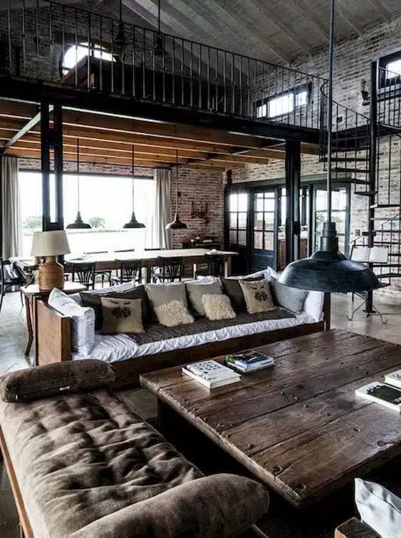Loft decorado com madeira de demolição e elementos industriais, como sofás bem adornados e mesas de centro de madeira recuperada.