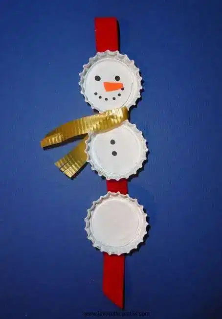 DIY Christmas Decorations: Create Your Own Holiday Cheer 5 Bonequinho de neve feito com tampinhas de garrafa, pintado com tinta branca, laranja e preta.