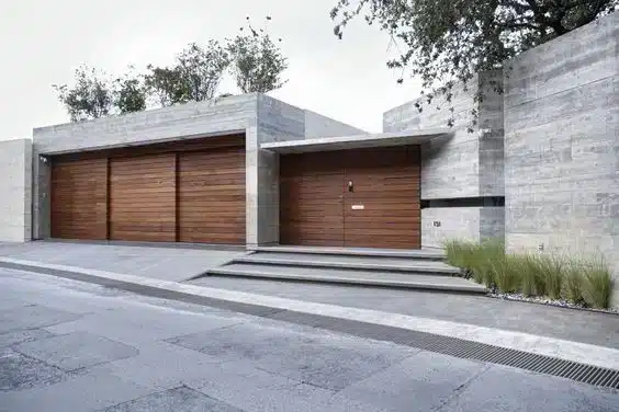 Fachada de casa com estruturas alinhadas de concreto e um portão de madeira.